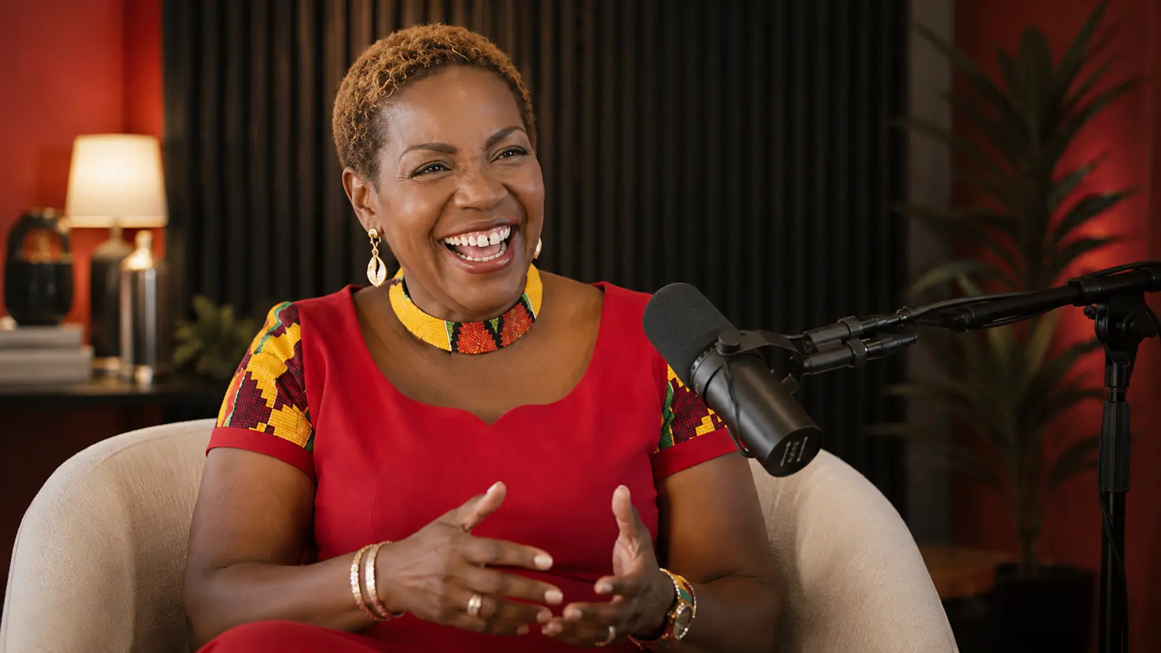 Lily Naadu Mensah recording in a warm studio with a podcast microphone